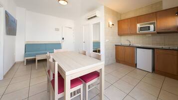A compact kitchen with a dining table, a microwave, and a refrigerator.