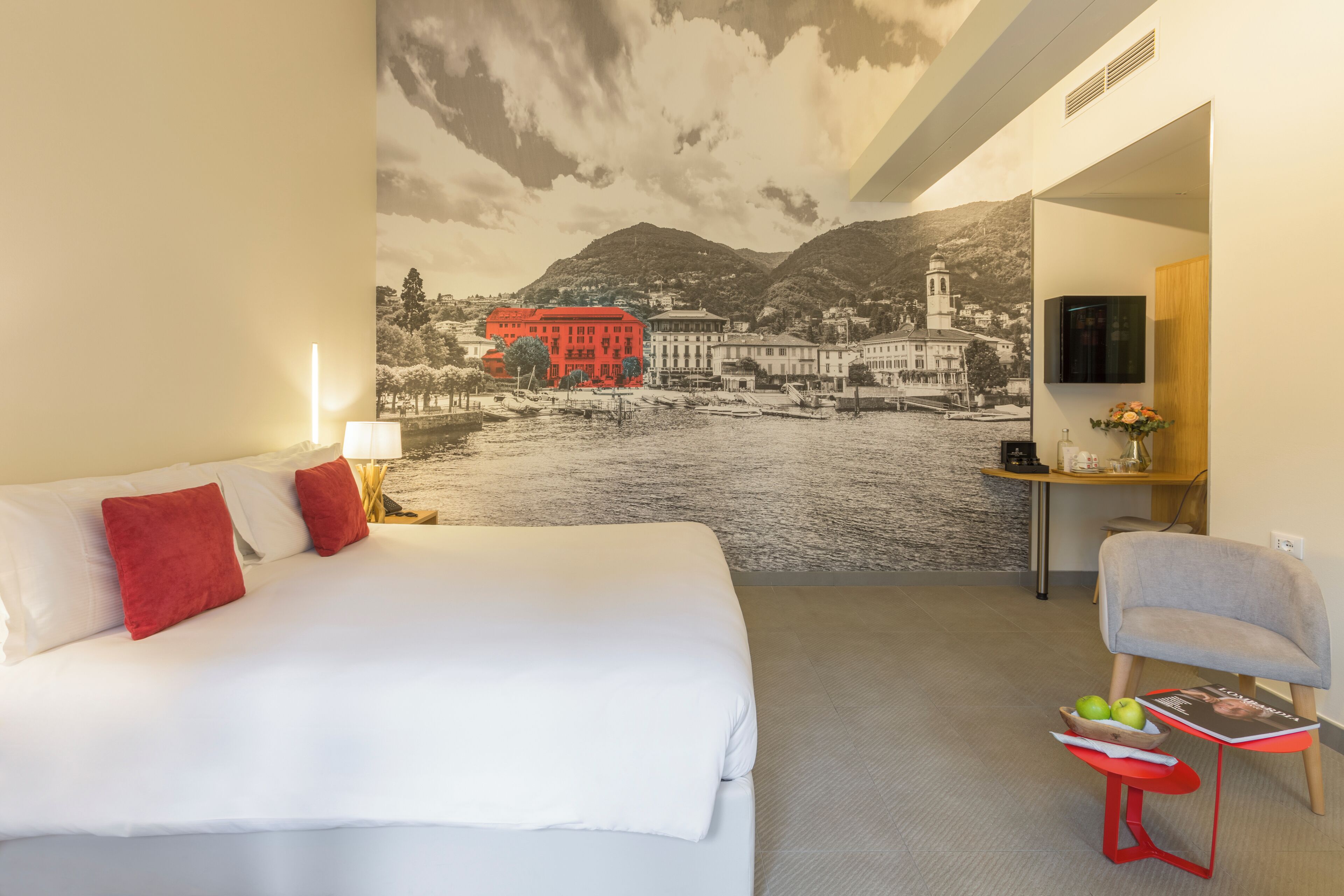 Une chambre d’hôtel avec un lit, un bureau, une chaise et une fresque murale.