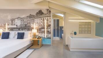 Une chambre d’hôtel moderne dotée d’un grand lit, d’une table de chevet avec une lampe, d’une vue sur le paysage urbain par la fenêtre, et d’une salle de bain séparée avec une baignoire et une douche.