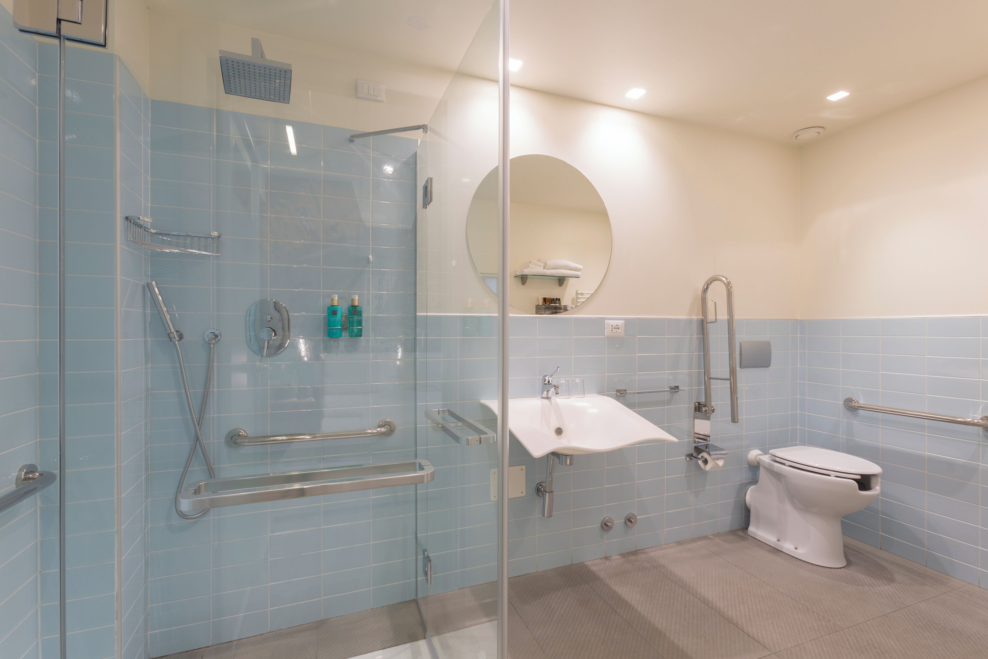 A bathroom with a glass-enclosed shower, a white sink, and a toilet.