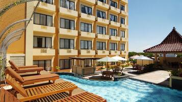 Una piscina al aire libre, sombrillas, sillones reclinables de piscina