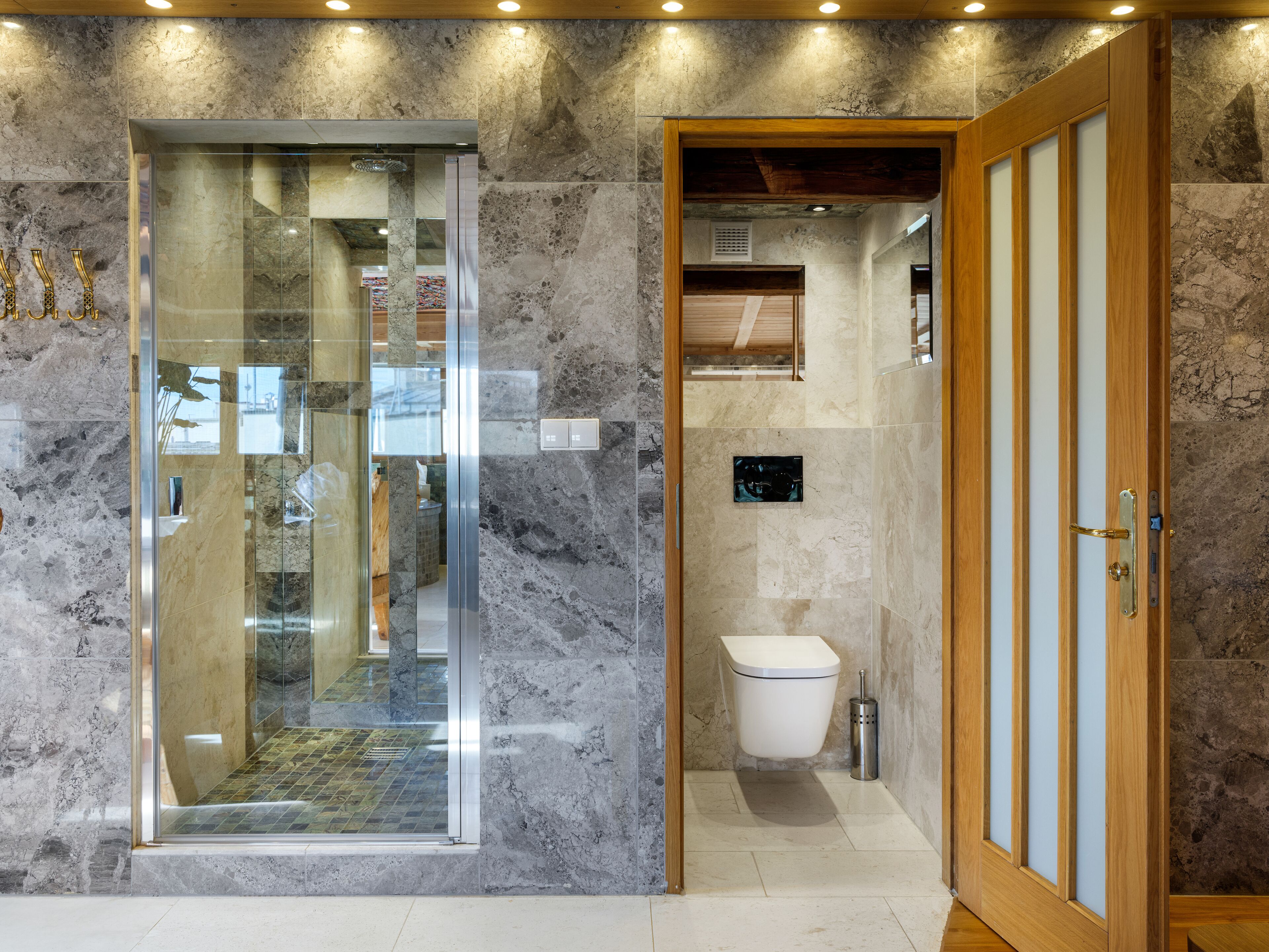 Un bagno moderno con doccia vetrata, una porta in legno e un water.