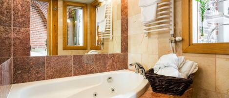 Une salle de bain moderne avec une grande baignoire, une porte en bois et un miroir qui reflète la pièce.
