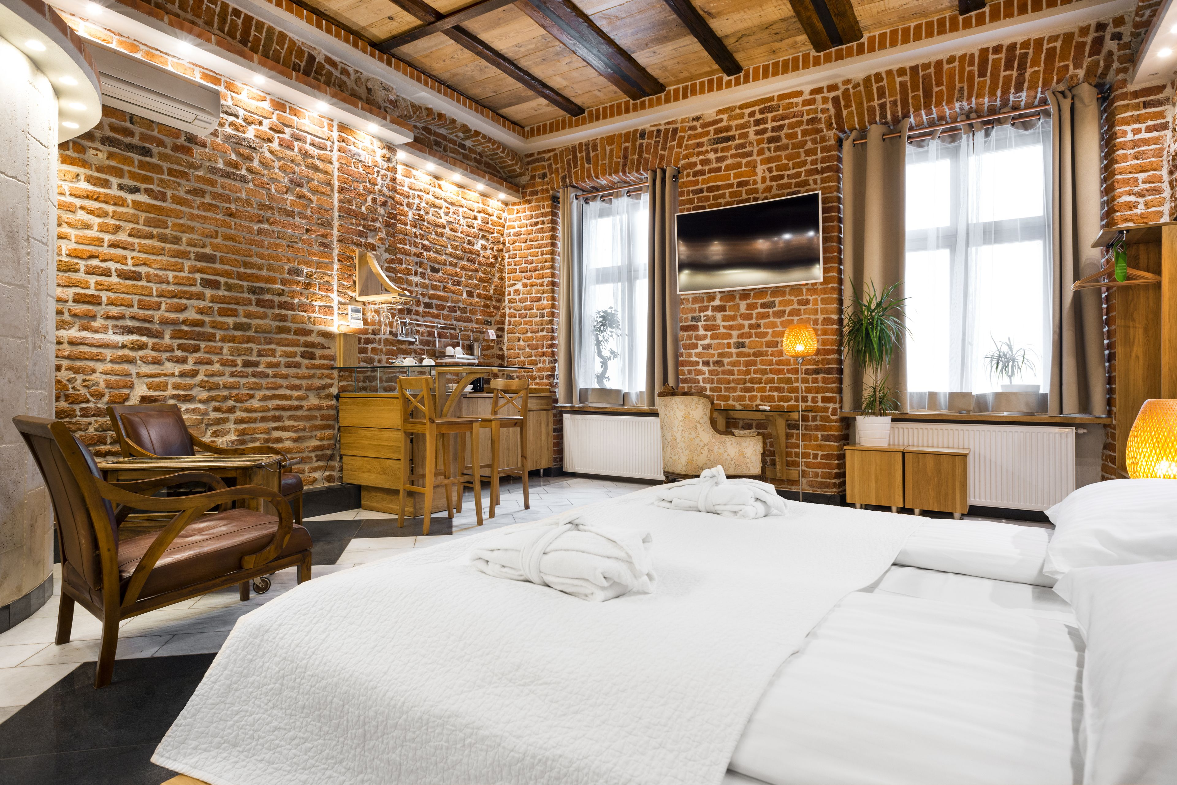 Habitación de hotel con pared de ladrillo, una cama grande, un escritorio y una silla.