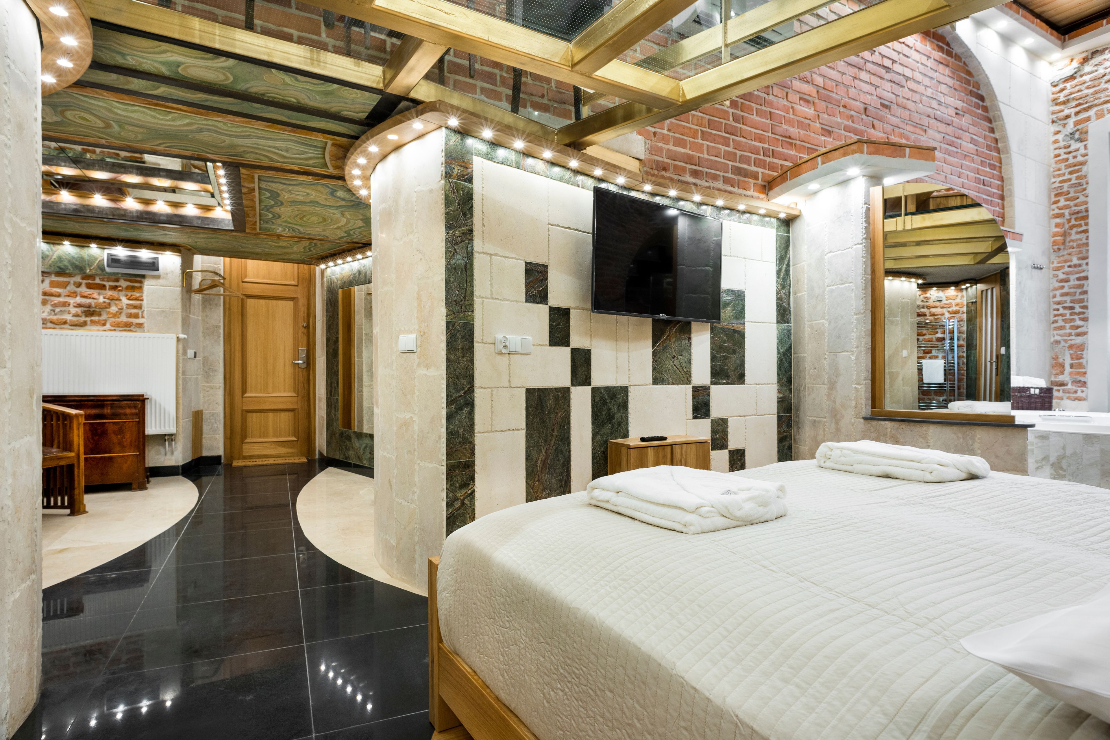 A modern hotel room with a large bed, a flat-screen TV, and a bathroom with a mirror and sink.