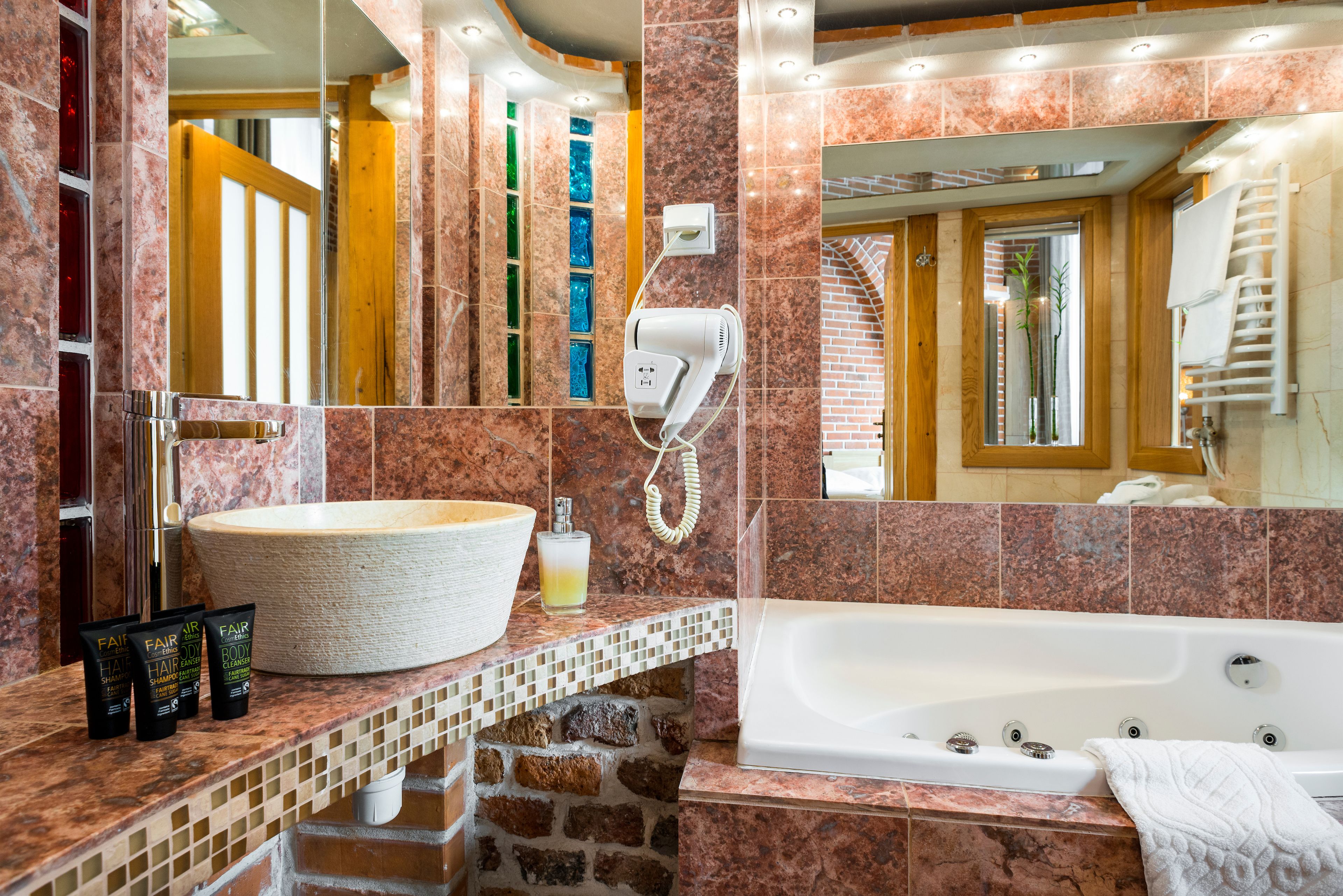 Une salle de bain avec un grand lavabo, un sèche-cheveux et des articles de toilette posés sur le comptoir.