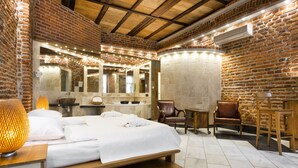 A hotel room with a brick wall, a wooden ceiling, a large bed, a desk, and a chair. - Aparthotel Stare Miasto (Kraków)
