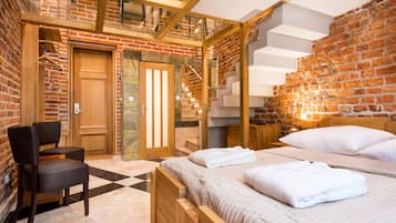 A modern hotel room with a brick wall, a wooden bed, a chair, and a staircase.