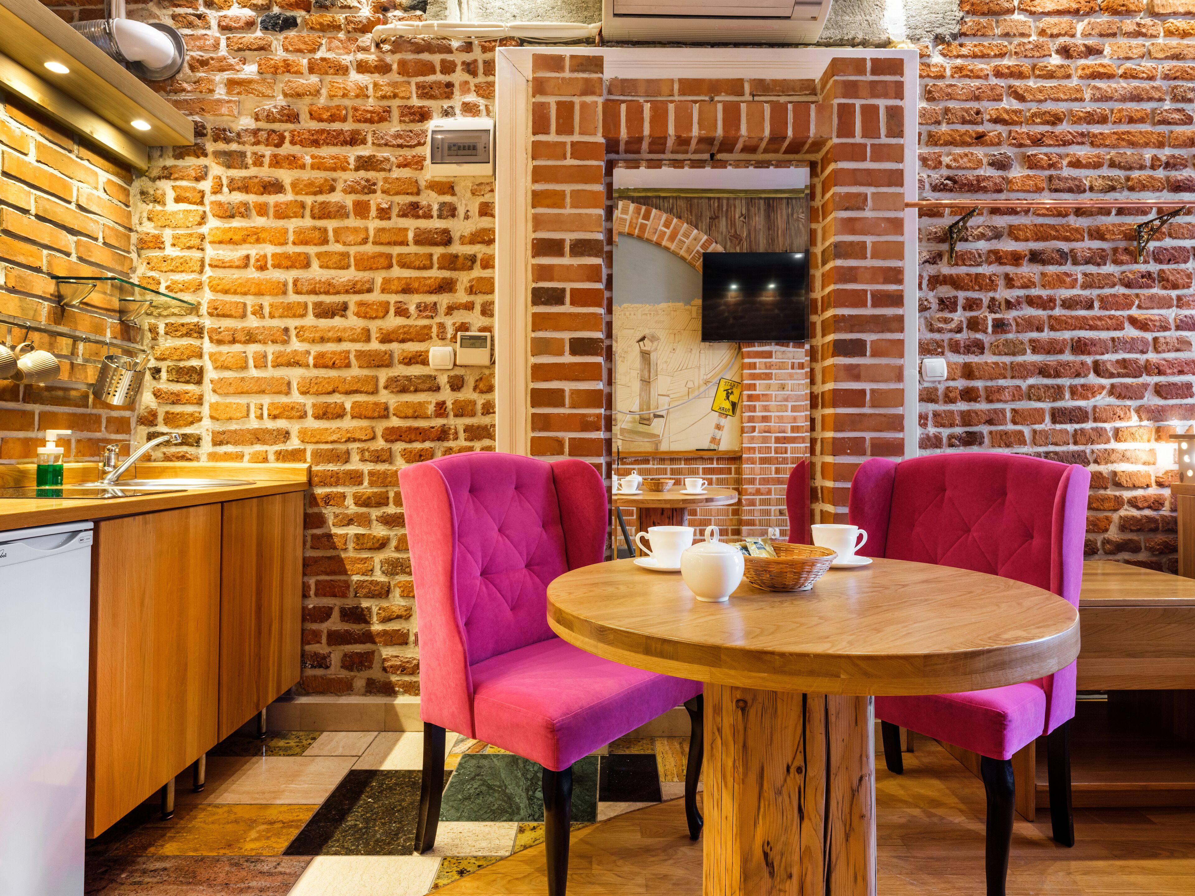 A cozy cafe with brick walls, wooden furniture, and a round table with chairs.
