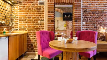 Een knus café met bakstenen muren, houten meubels en een ronde tafel met stoelen.