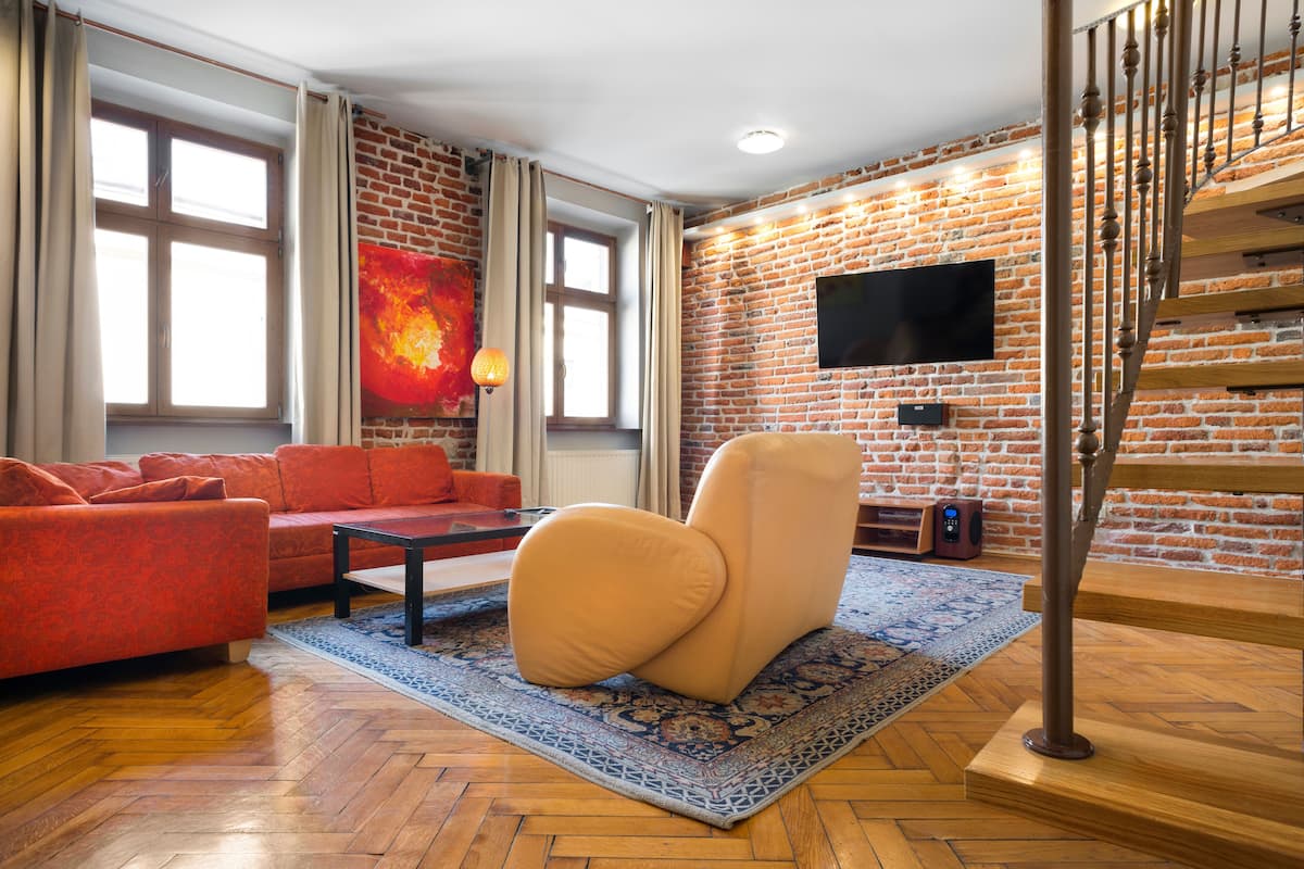A modern living room with a brick wall, a sofa, a coffee table, and a staircase.