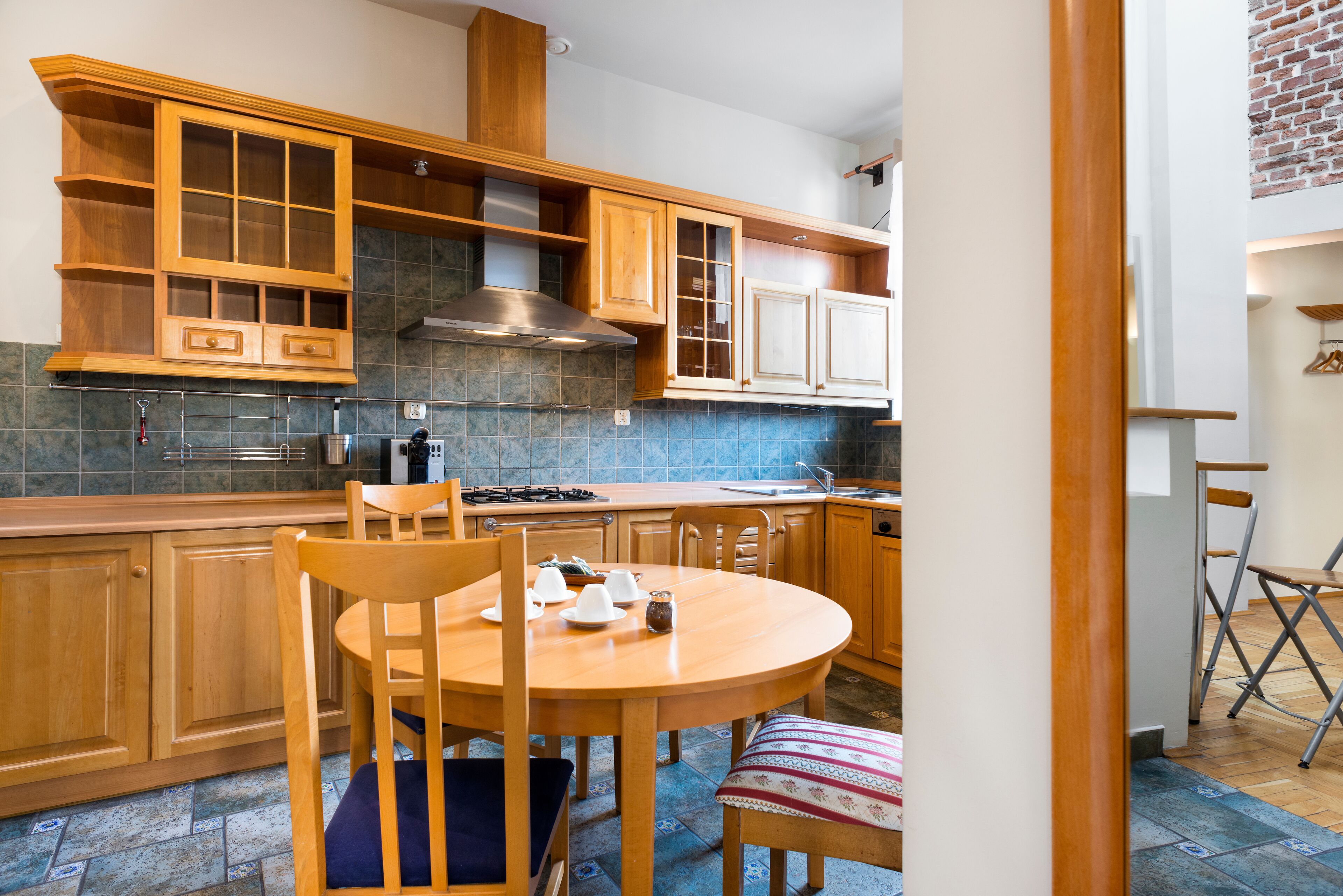 Een keuken met houten kastjes, een ronde tafel en stoelen.