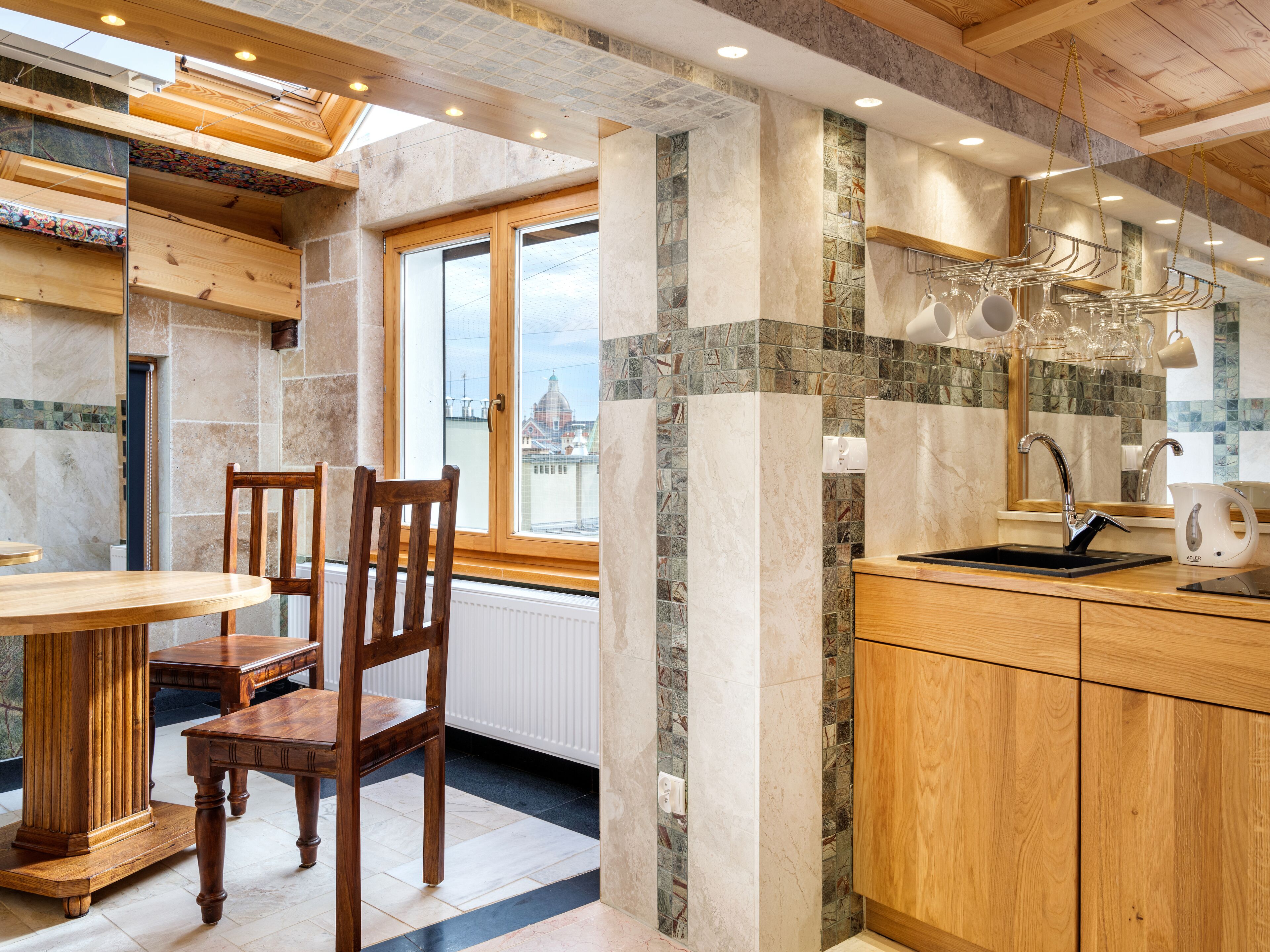 Una cocina moderna con una mesa y sillas de madera, horno empotrado y un amplio ventanal con vistas a la ciudad.