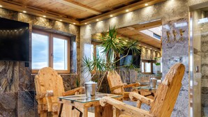 A dining area with wooden chairs and a glass table, surrounded by stone walls and a large window. - Aparthotel Stare Miasto (Kraków)