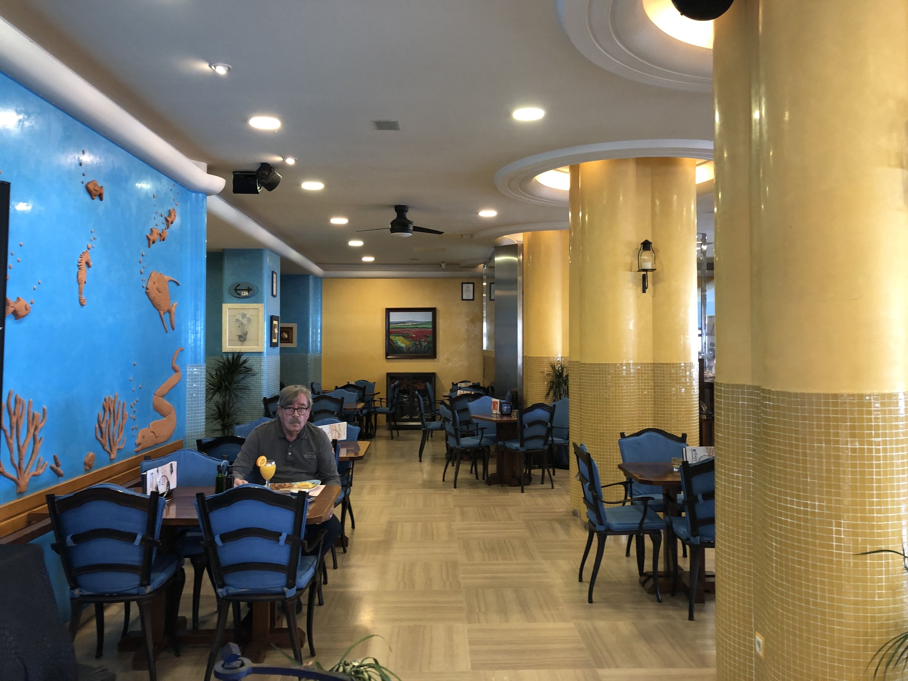 A restaurant with blue walls, wooden tables, and chairs.