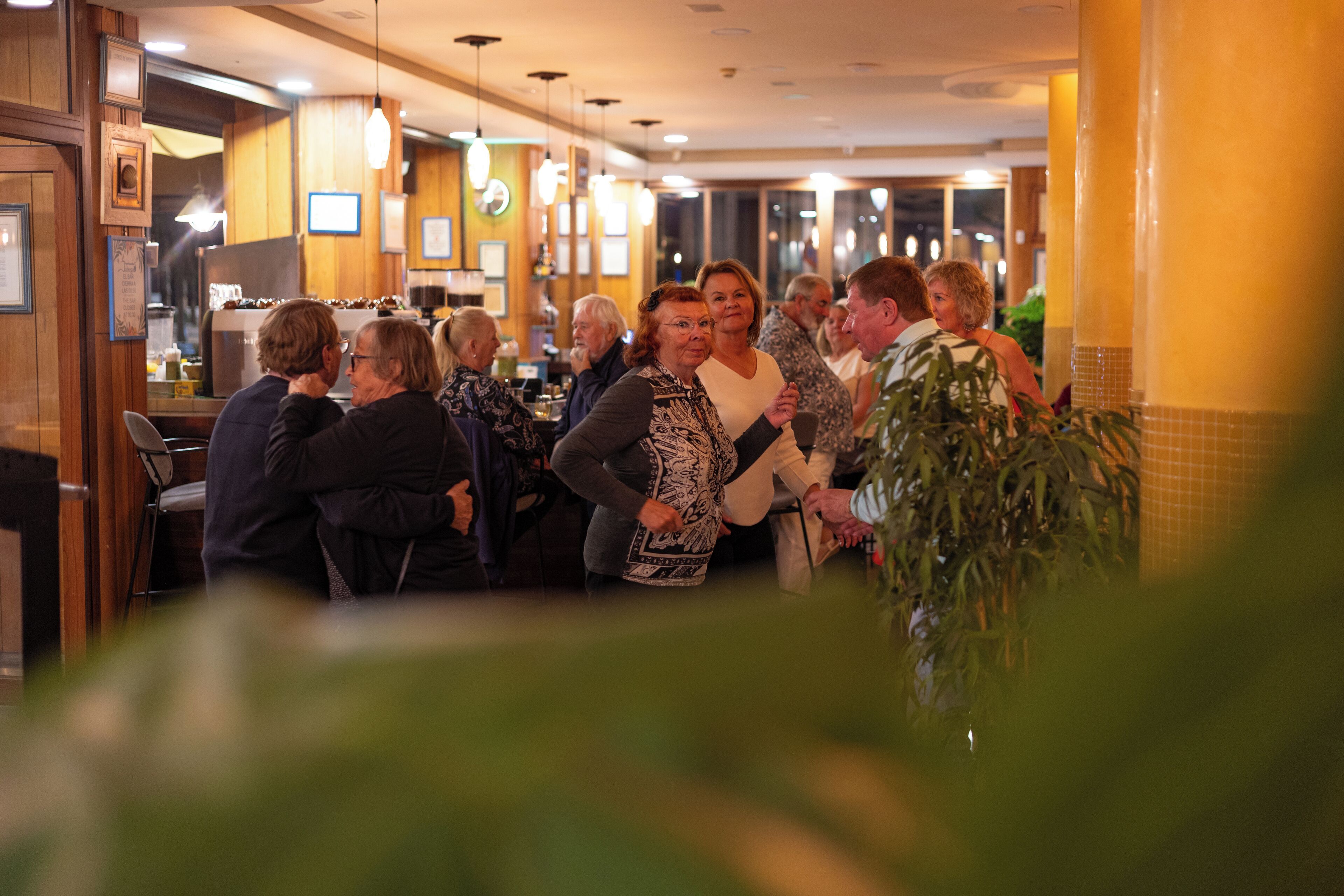 Un grupo de personas en un ambiente interior cálido, con paneles de madera e iluminación colgante.