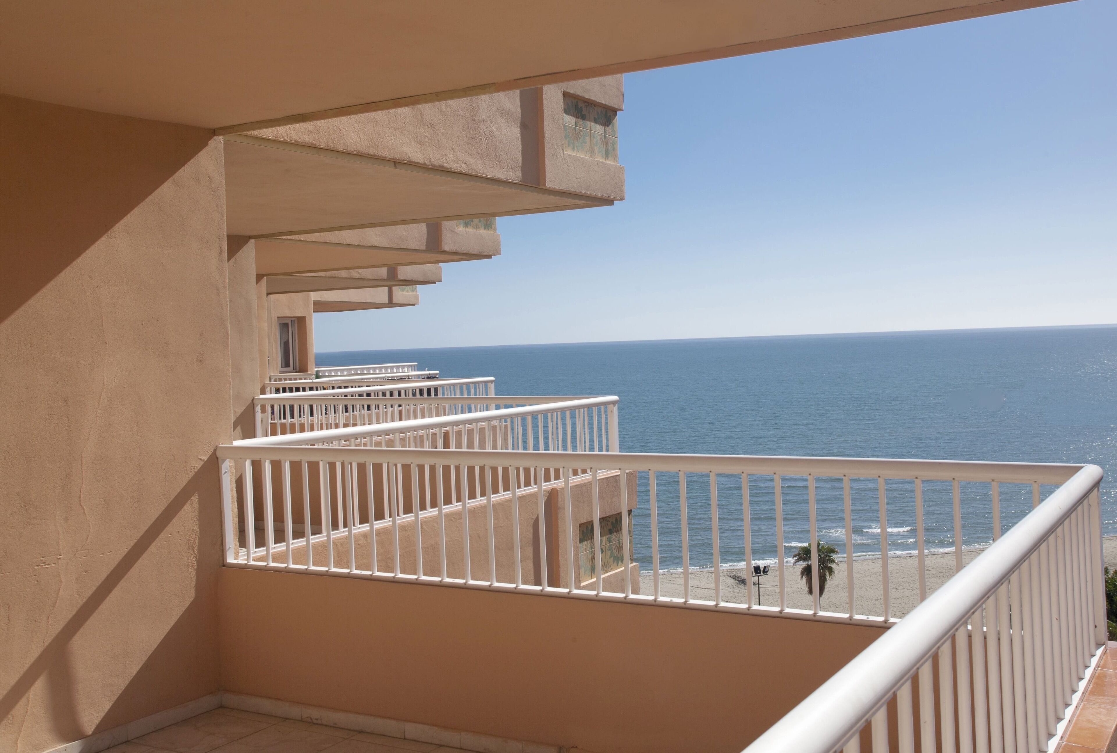 A balcony with a view of the ocean and beach.