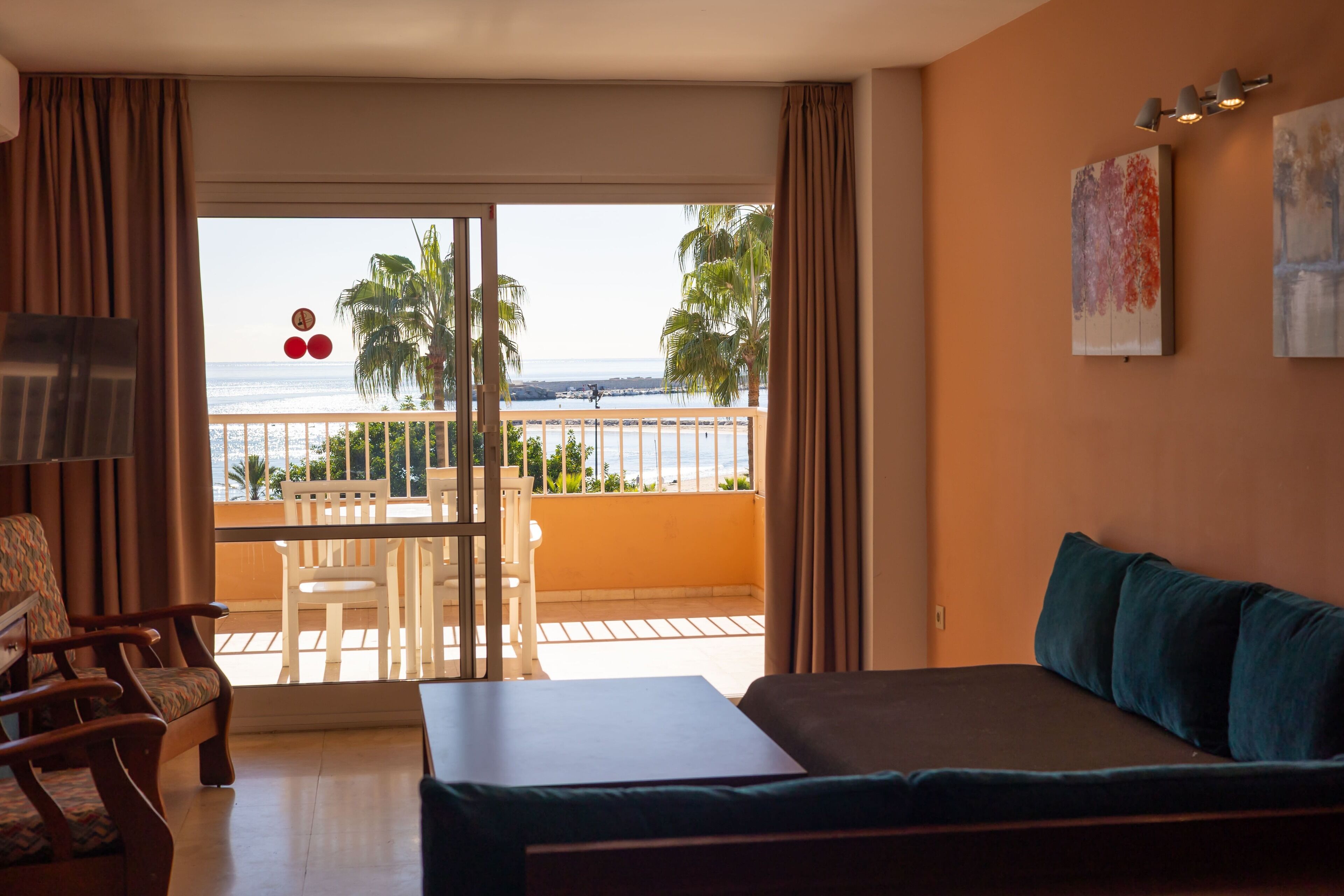 Una habitación de hotel con balcón, una cama, una silla y una mesa.