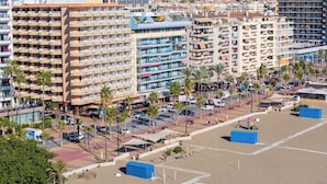 Un paisaje urbano costero con hoteles de gran altura, palmeras y una zona de playa arenosa.