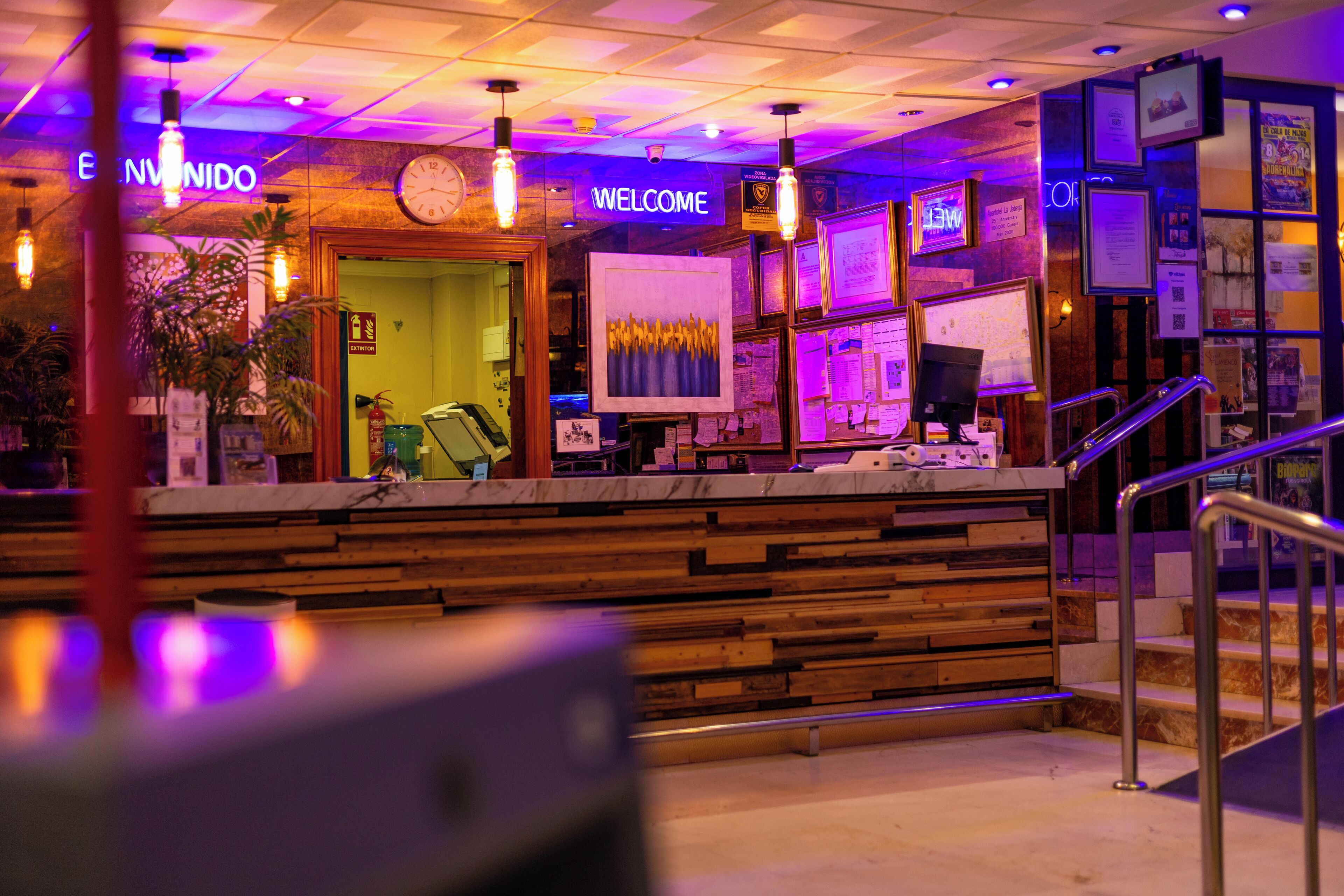 A reception area with a wooden counter, a clock, and a 'Welcome' sign.