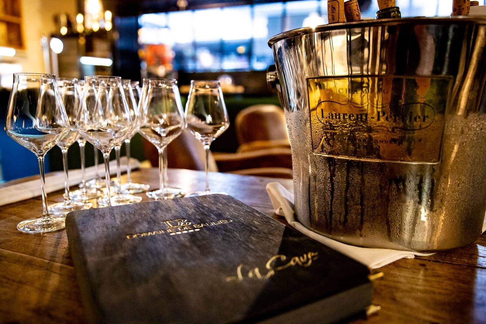 A bar setting with a champagne bucket labeled "Laurent-Perrier" and a menu titled "Le Cuvée."