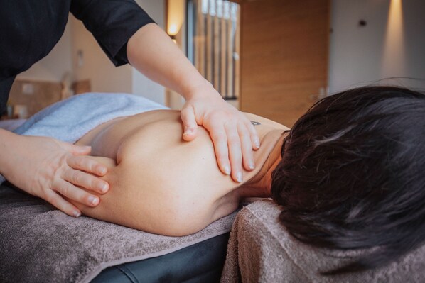 A massage therapy session in a room with a wooden door and a window with blinds.