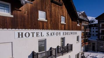 Un cartello con la scritta 'HOTEL SAVOY EDELWEISS' su un edificio bianco con rivestimento in legno.