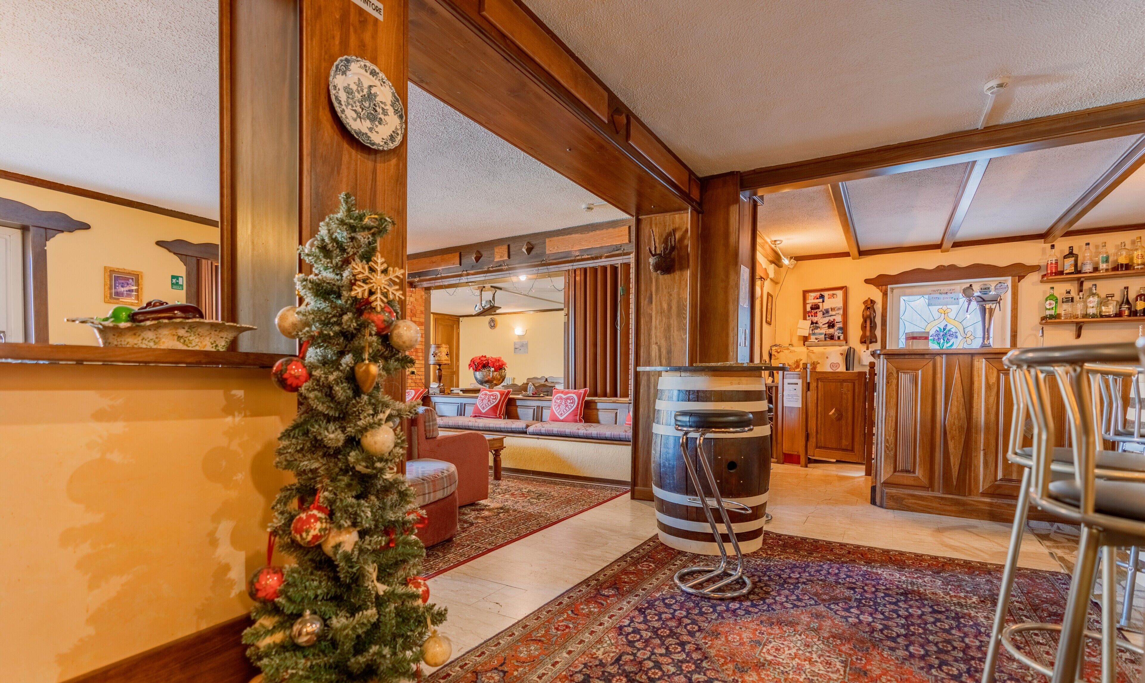 Un ambiente accogliente con un albero di Natale, un angolo bar e una zona salotto con un tappeto a motivi.