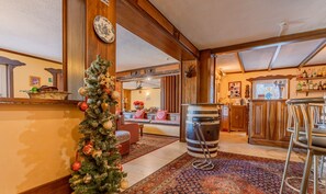 Un interior acogedor con un árbol de Navidad, una zona de bar y un espacio de estar con un tapete estampado.
