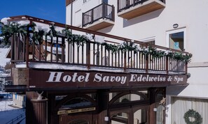 Un hotel con un balcón decorado con plantas y nieve.