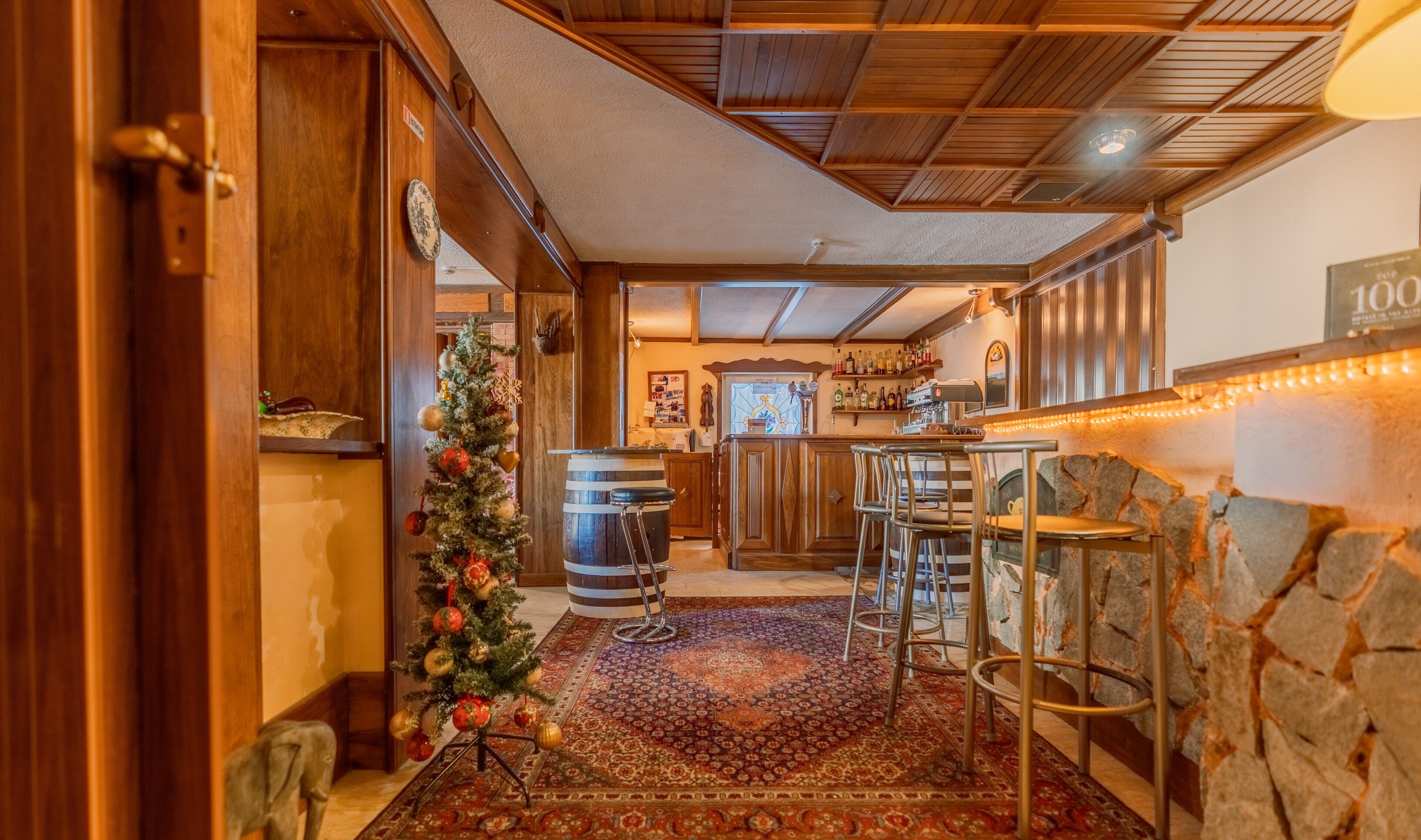 Un ambiente accogliente con un albero di Natale, una parete in pietra e un’area bar.