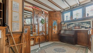 Un interior tradicional con paneles de madera, un piano y una alfombra estampada.