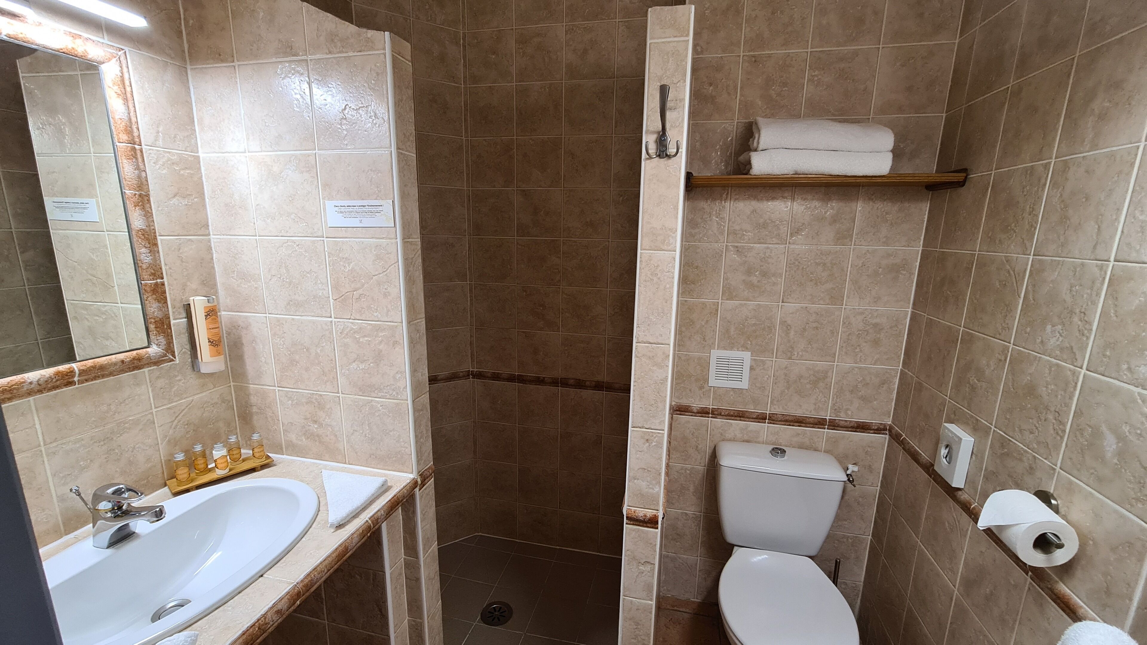 Ein Badezimmer mit Waschbecken, Spiegel, Toilette, Dusche und Handtuchhalter.