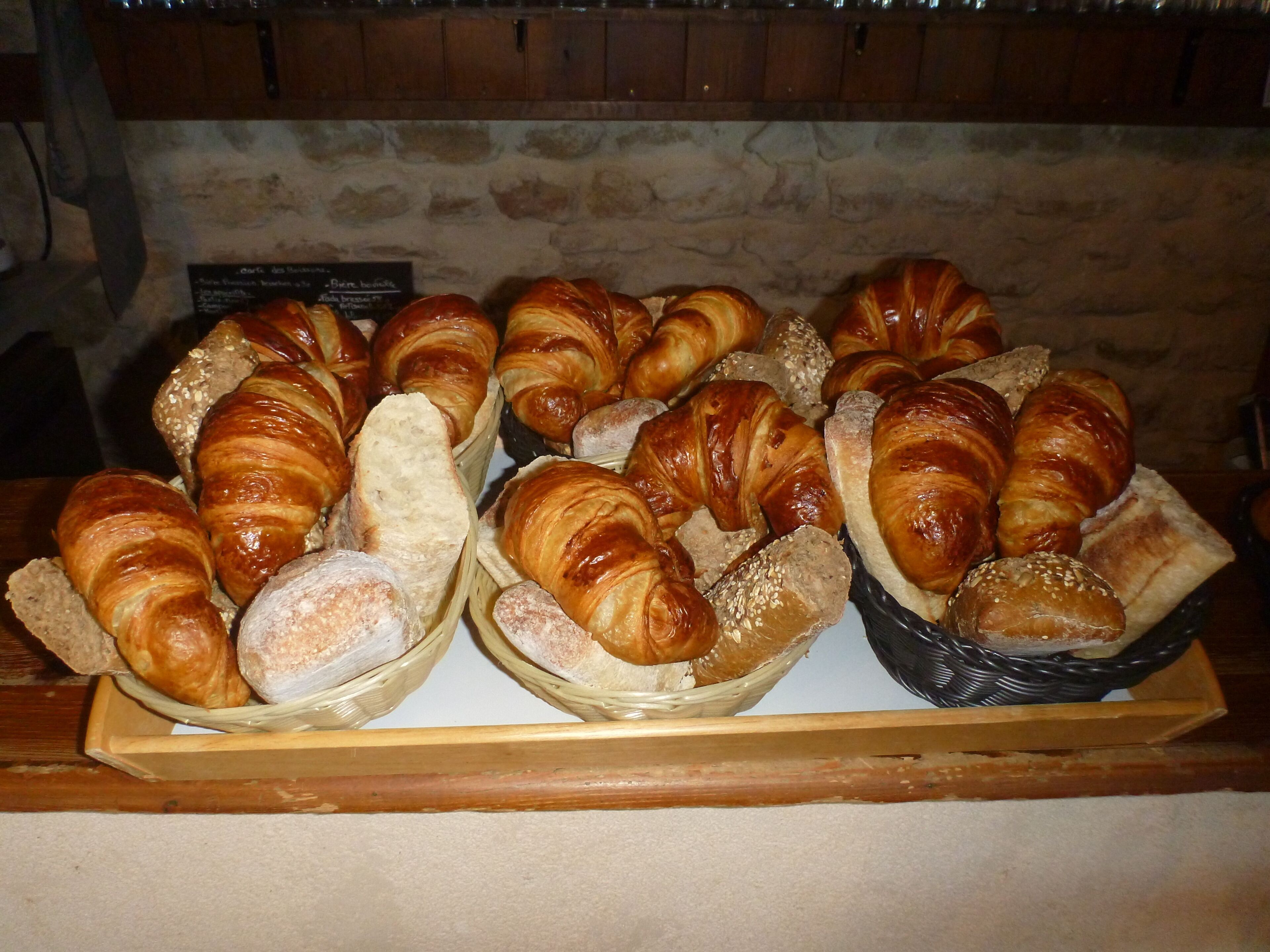 A variety of pastries displayed on a wooden tray in a bakery setting.