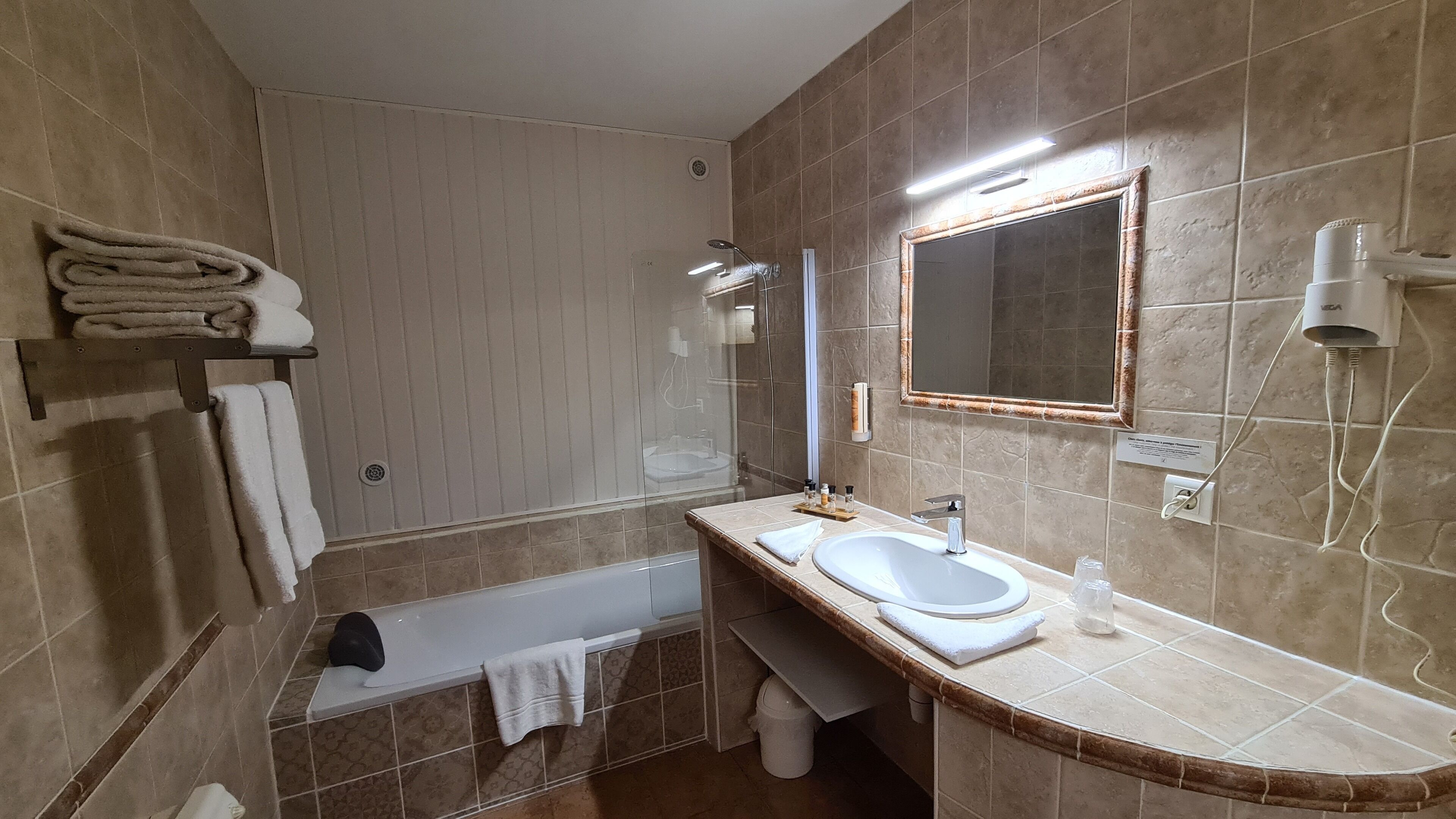 Une salle de bain avec une baignoire, un lavabo, un miroir et un porte-serviettes.
