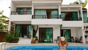 A two-story building with a swimming pool, balconies, and outdoor seating.