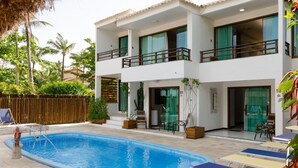 A two-story house with a swimming pool, outdoor furniture, and a wooden fence. - Pousada Rigatoni Beach (Porto Seguro)