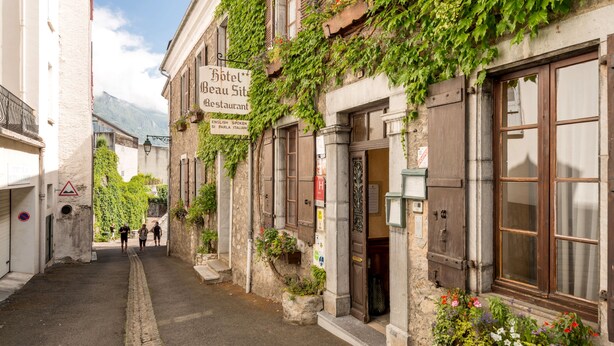 Una calle estrecha flanqueada por edificios, incluyendo un hotel con un letrero que indica que es restaurante.