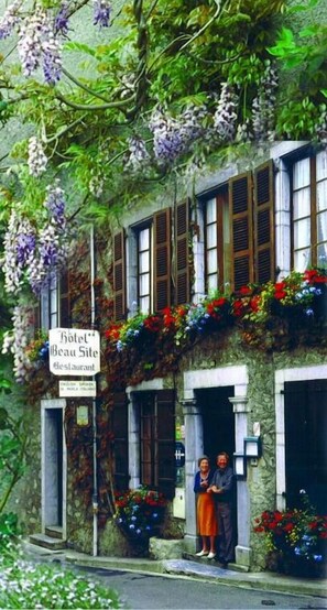 Un edificio con un letrero que dice "Hotel Beau Site Restaurant" y un letrero que indica que es una "Casa de Campo Inglesa Tradicional".