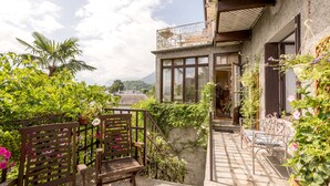 Un patio con un sendero de piedra, sillas de madera y un banco de metal.