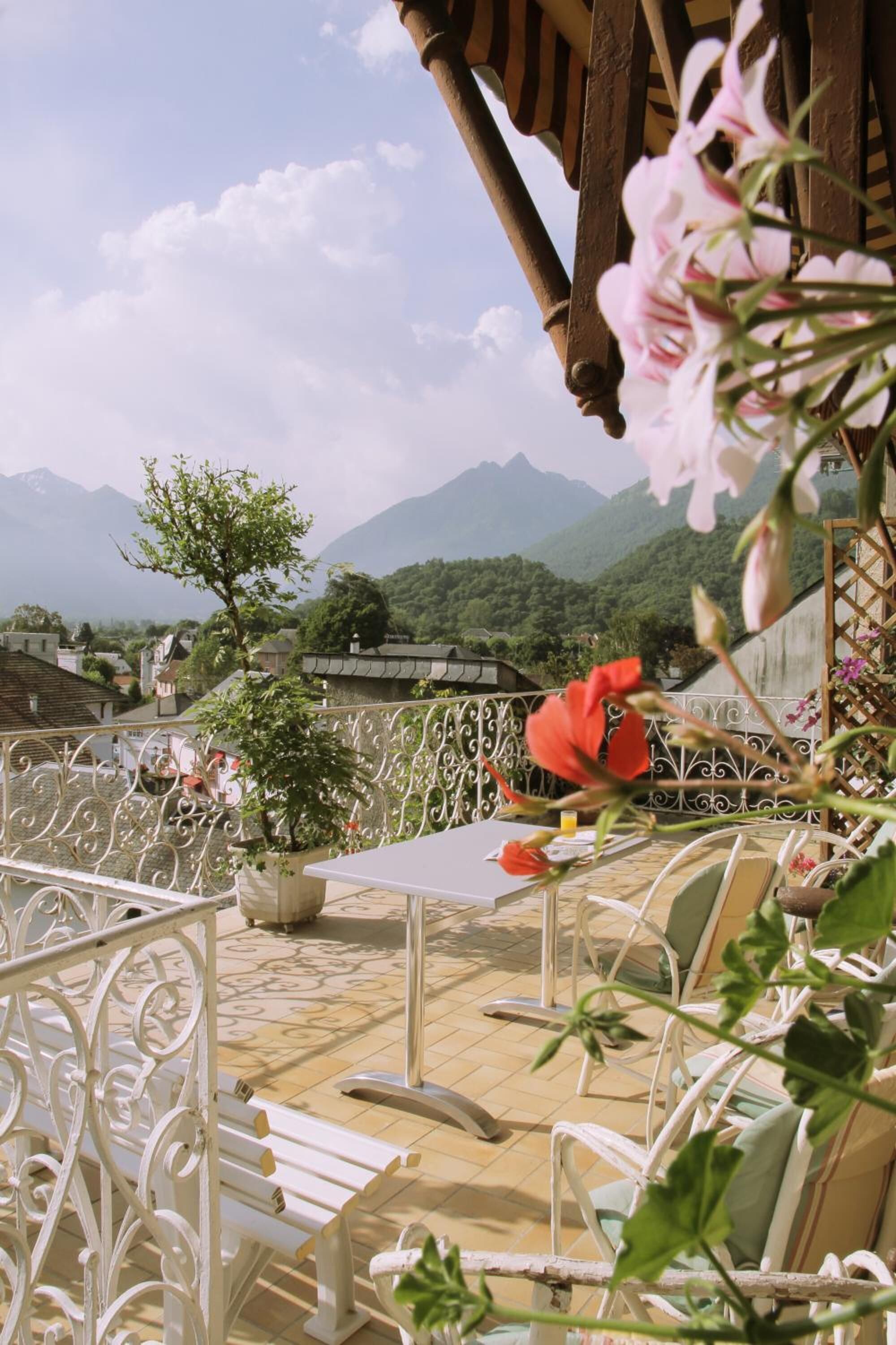 Una terraza con mesa y sillas, una planta en maceta y vistas a las montañas.