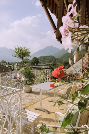 Una terraza con mesa y sillas, una planta en maceta y vistas a las montañas.