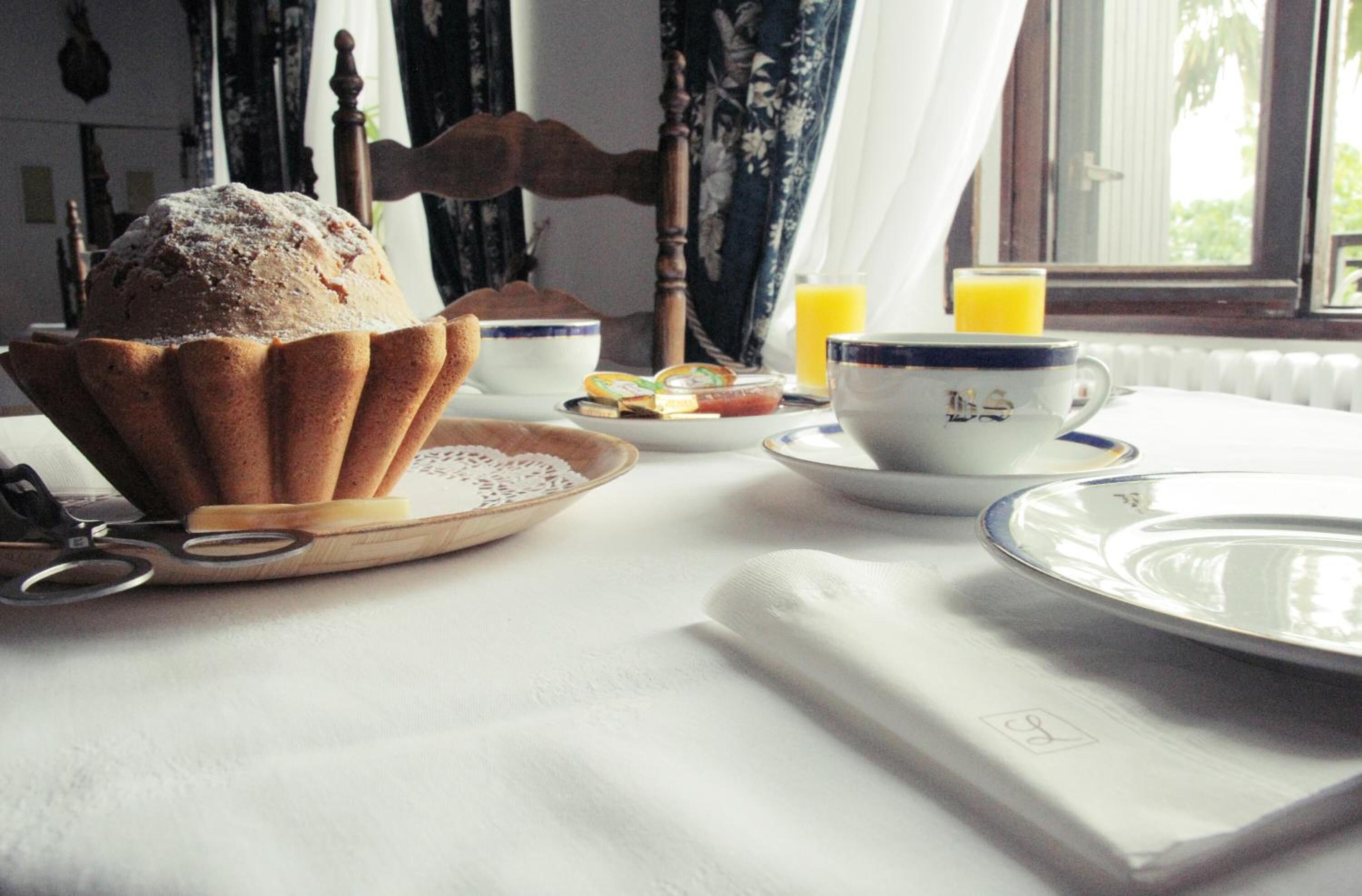A breakfast setting with a muffin, tea cups, and a glass of orange juice on a table.