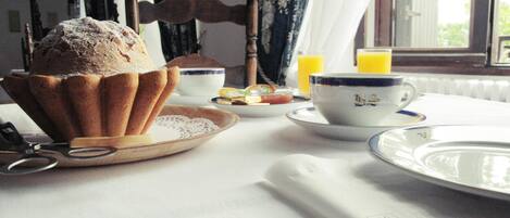 A breakfast setting with a muffin, tea cups, and a glass of orange juice on a table.