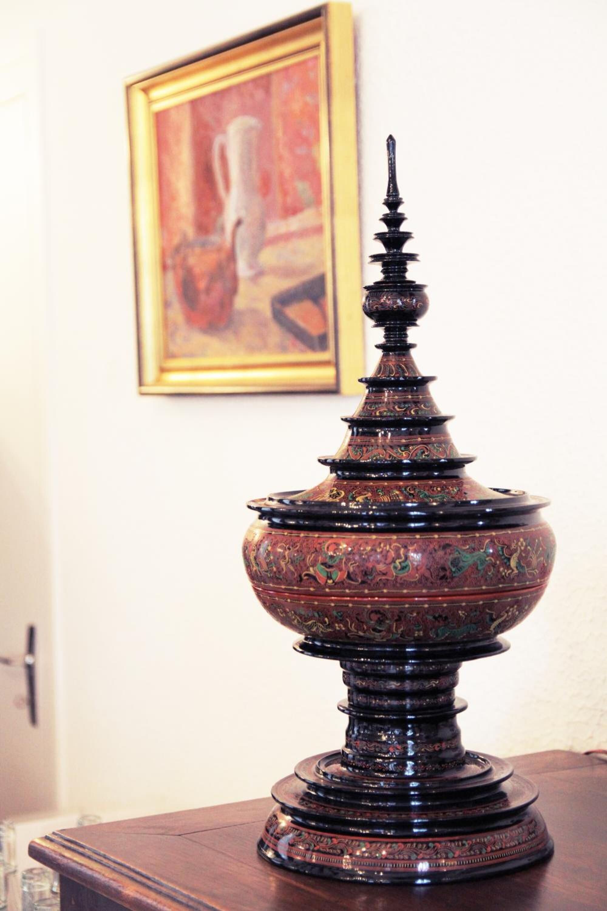 Un jarrón metálico decorativo con diseños intrincados sobre una superficie de madera.