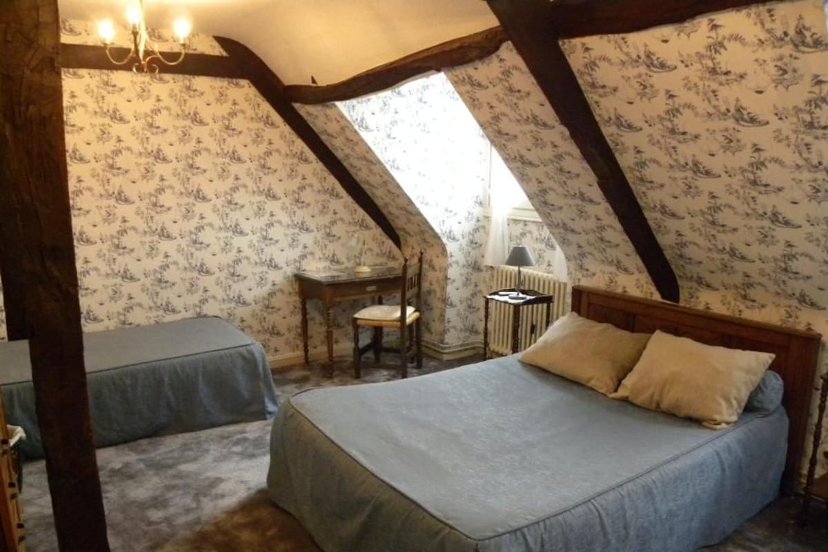 Une chambre à coucher avec un lit, deux tables de chevet, une chaise et une fenêtre.