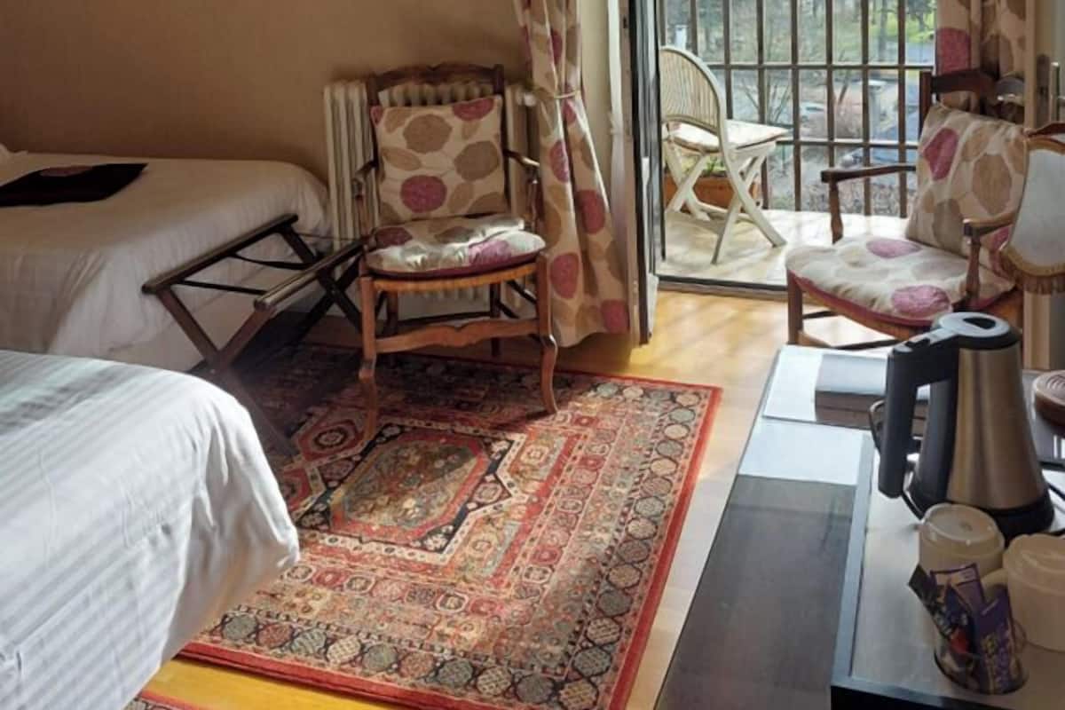 Hotelkamer met een bed, een stoel, een bureau met koffiezetapparaat en uitzicht op bergen door het raam.
