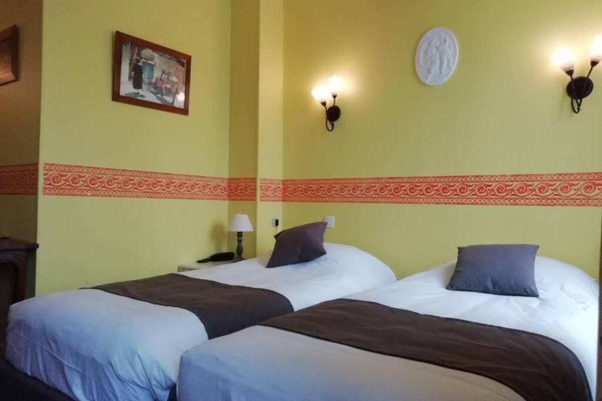 A hotel room with two beds, a decorative wall with a patterned border, and wall-mounted light fixtures.