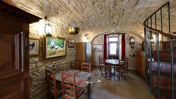Un coin repas rustique avec des murs en pierre, des meubles en bois et un escalier en colimaçon.