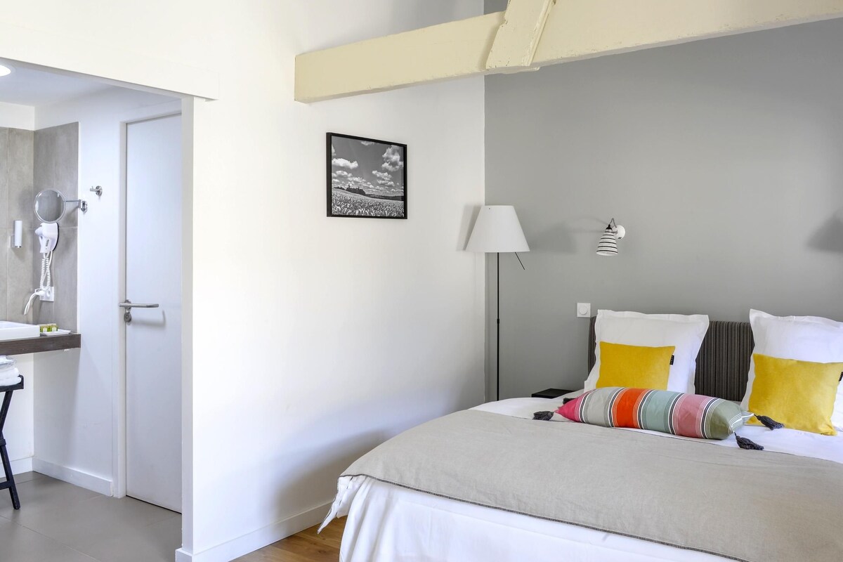 A modern bedroom with a bed, bedside lamps, and a framed picture on the wall.